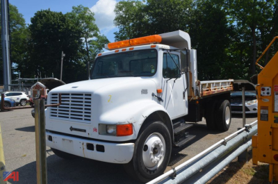 Dump truck 1996 International 4700 in/service showing white cab and dump bed with orange lights on top.
