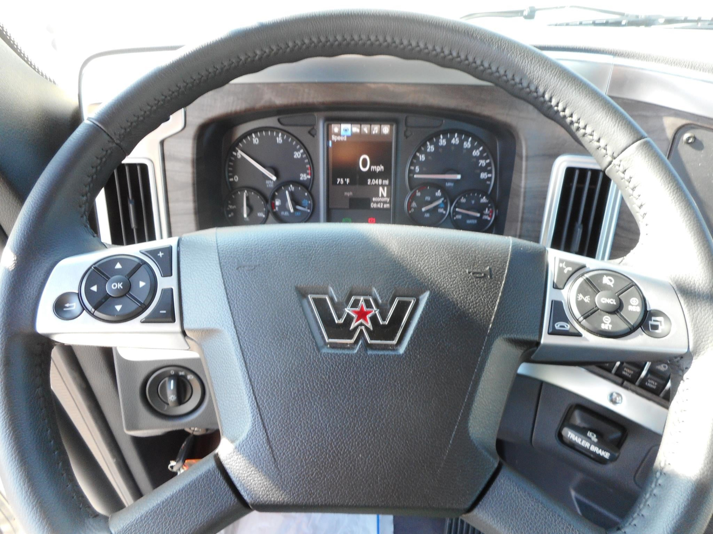 Steering wheel of a Western Star truck cab with dashboard gauges visible through the wheel