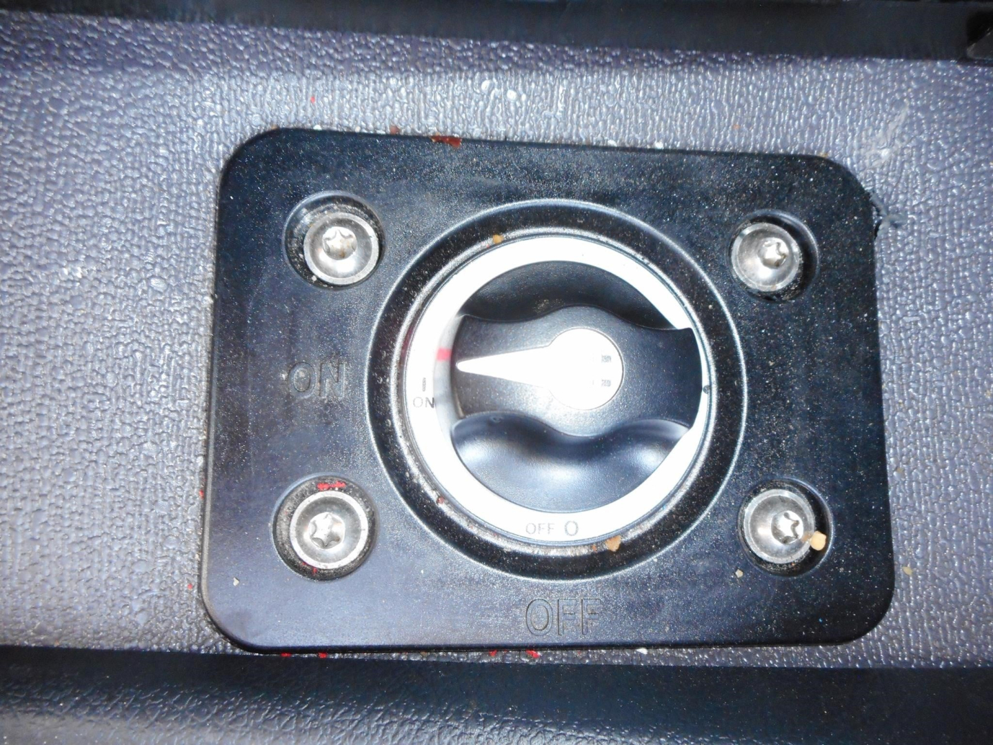 Rocker switch panel with circular dial labeled ON and OFF, mounted in a textured surface inside a truck cab.