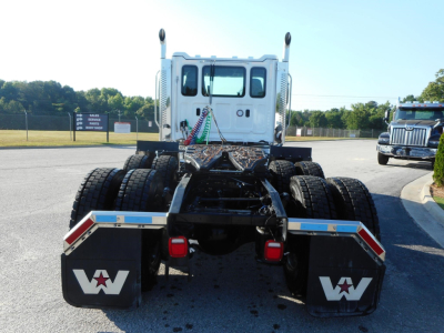 Rear view of a white 2026 Western Star 49X chassis with dual rear axles and mud flaps showing Western Star logo, connected to fifth wheel and air lines.