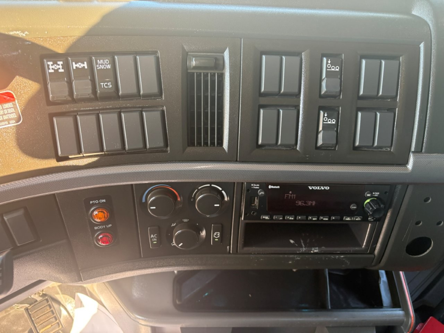 Volvo truck dash and control panel showing climate controls, switches, and aftermarket radio unit