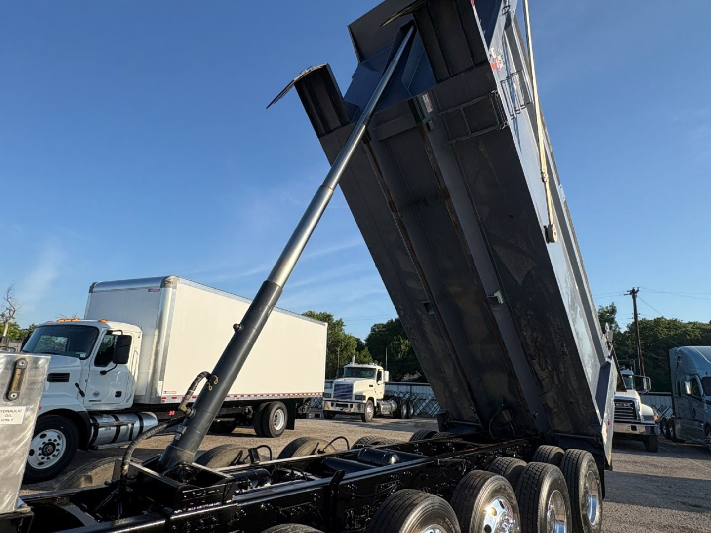 Volvo VHD series dump truck with raised bed and hydraulic ram, side view showing tandem rear axles and bumper tag.