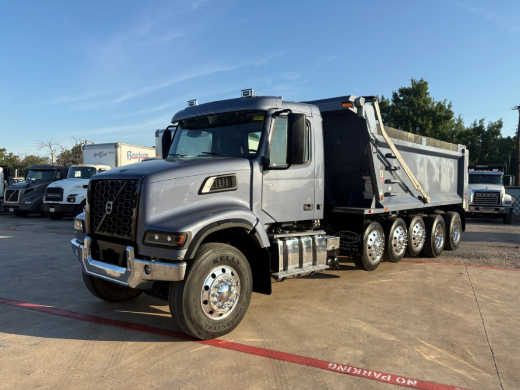 Volvo VHD dump truck in-side view showing large front grille, dual mirrors, multiple axles, and dump bed.