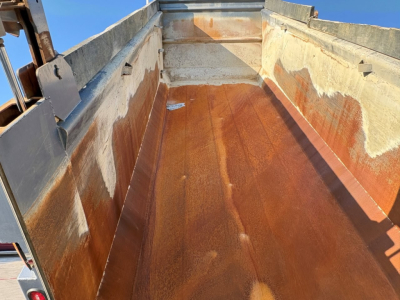 Dump truck bed interior showing rust-toned steel lining and sidewalls with wear marks.