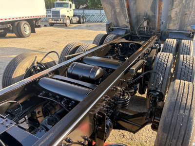 Vehicle chassis of a Volvo VHD dump truck showing the frame, suspension, driveshaft, and fuel tanks with hydraulic components in view.