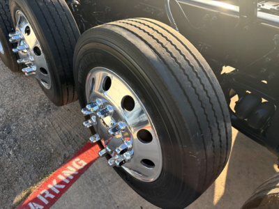Truck wheel close-up showing dual rear tires and chrome lug nuts on a Volvo VHD truck.