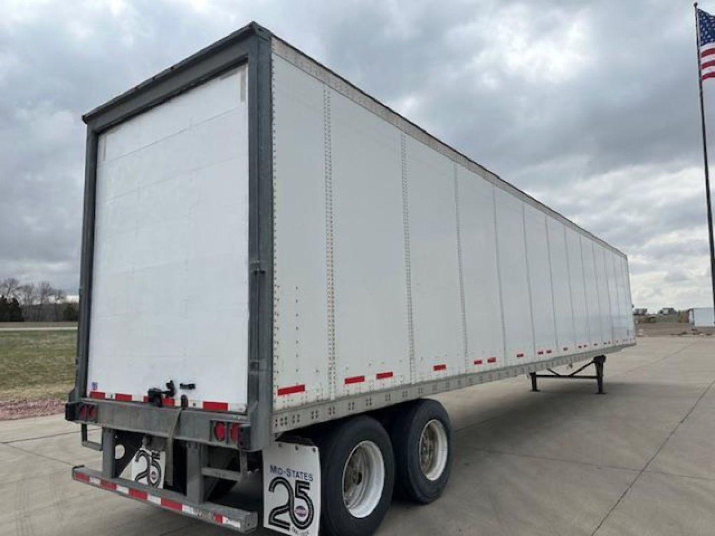 Trailer side view showing a 2014 Wabash van trailer with white walls, dual rear axle, and rear bumper with lights; VIN tag visible.