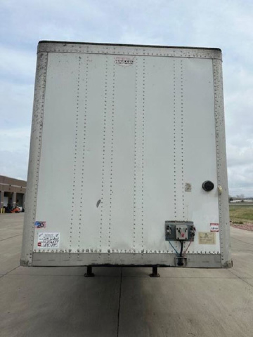 Rear view of a 2014 Wabash van trailer showing riveted aluminum exterior, rear doors, and maintenance/ID stickers.