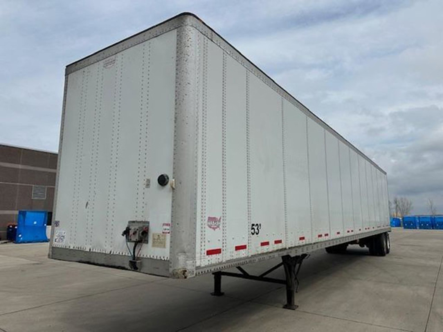 Trailer side view showing a white 53' Wabash van trailer with rear doors, corner post, and support legs visible.