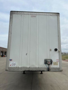 Rear view of a 2014 Wabash van trailer showing riveted aluminum exterior, rear doors, and maintenance/ID stickers.