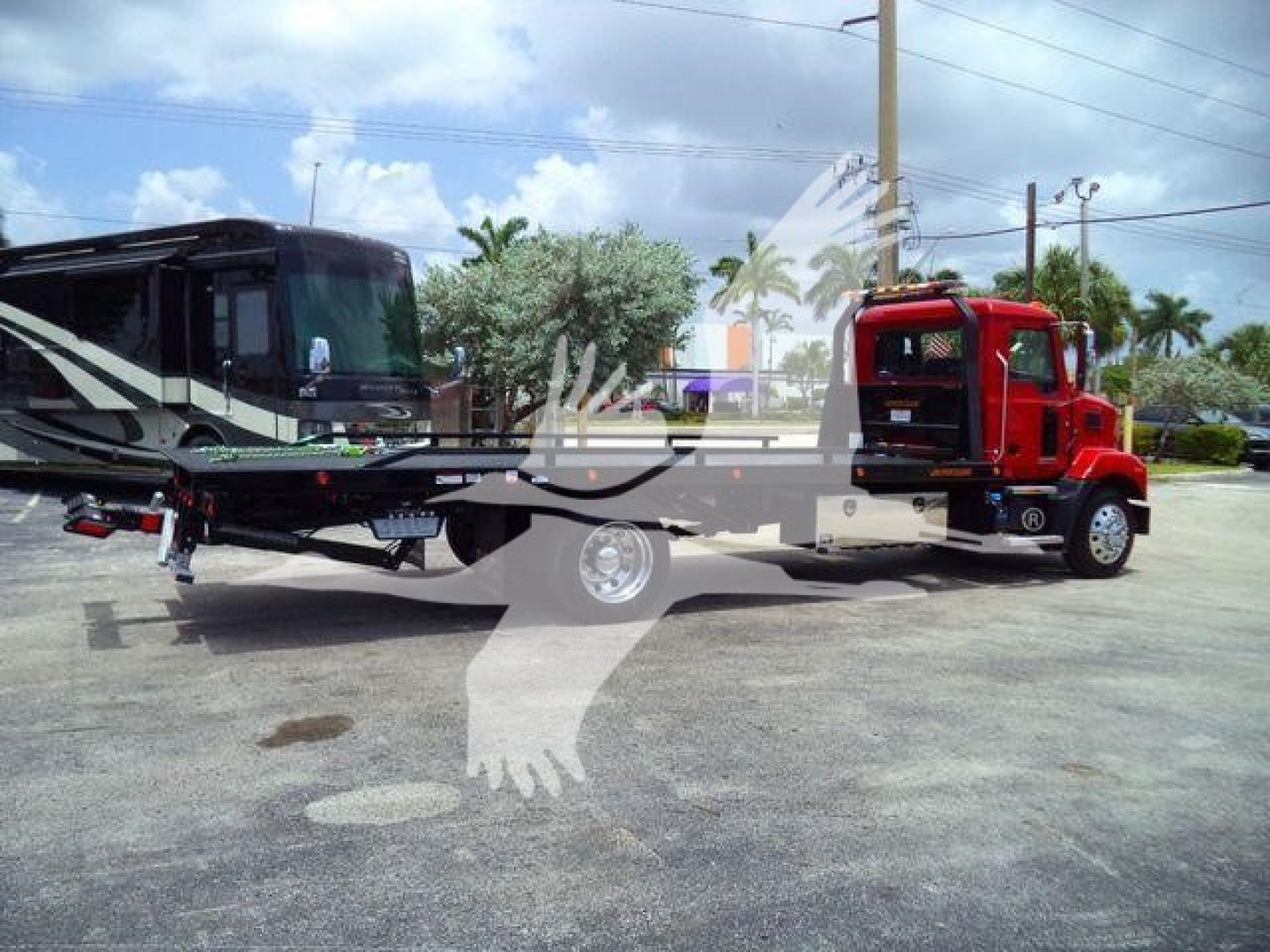 MD6 truck with flatbed rollback showing red cab and black trailer, dealership lot in background.