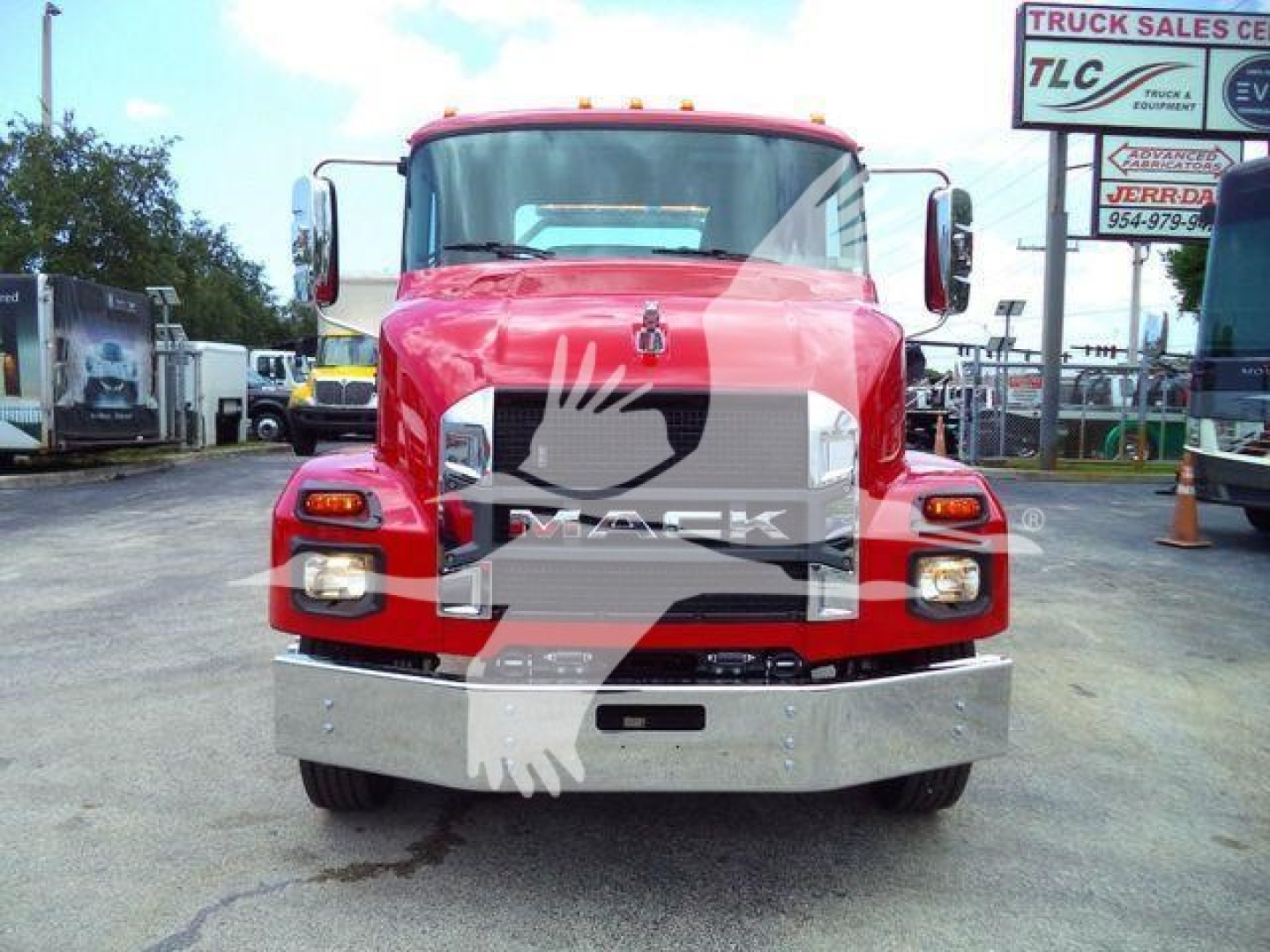 Front view of a red 2026 Mack MD6 truck in a dealership lot showing grille, bumper, headlights, and side mirrors.