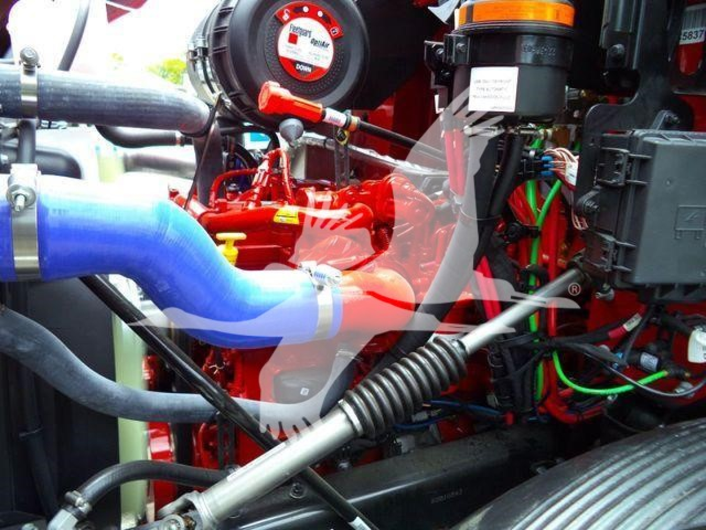 Mack MD6 engine bay showing red engine components, blue intercooler hose, black hoses, and wiring harnesses.