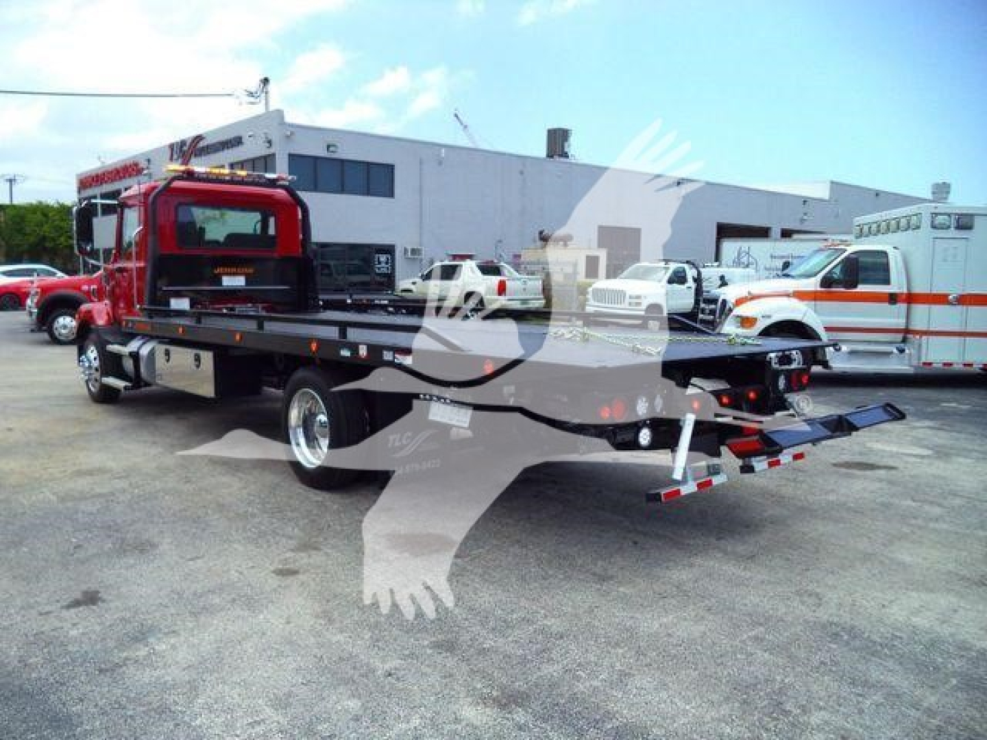 MD6 rollback truck with flatbed, red cab, black bed, and folded ramp at rear showing transport equipment.