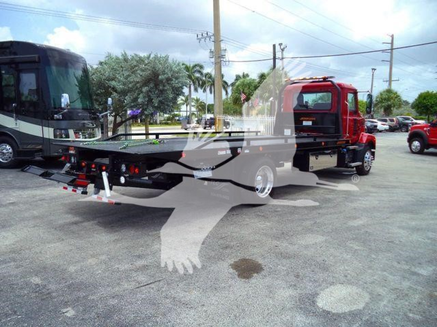 Mack MD6 rollback truck in parking lot showing flatbed with hydraulic winch and rear towing setup.