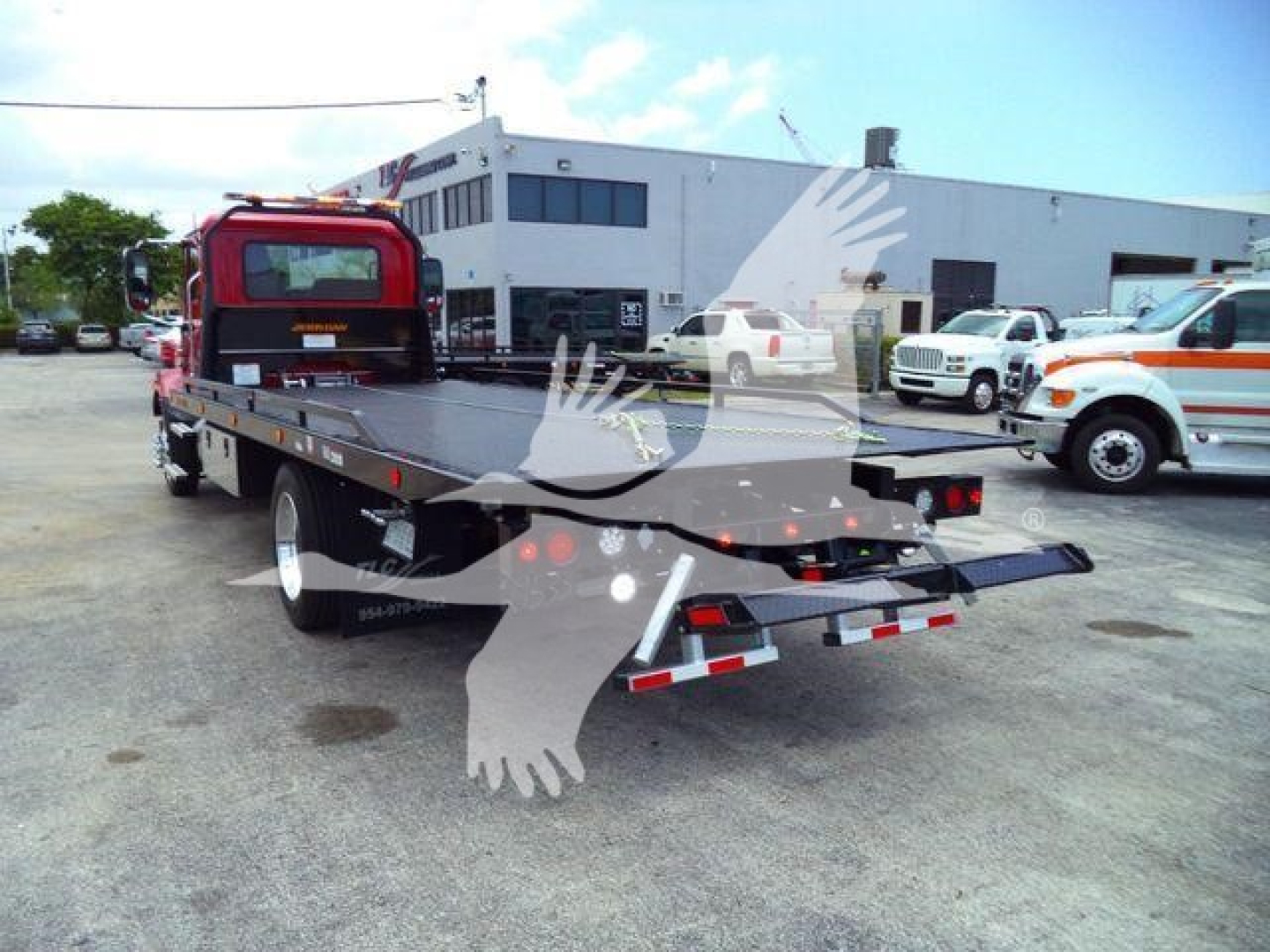Mack MD6 rollback truck flatbed rear view showing dealership lot.