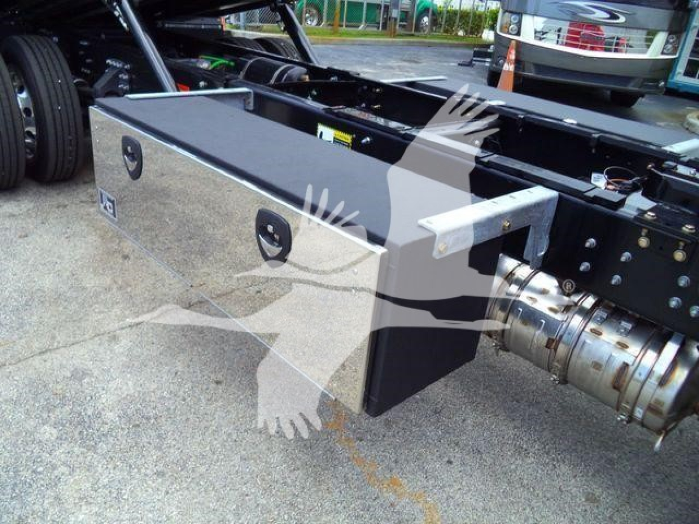 Mack MD6 rollback truck chassis showing a rectangular aluminum toolbox mounted near the cab, with rear wheel and drive components visible