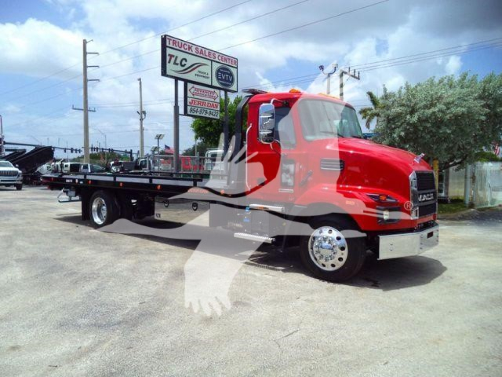 Mack MD6 w/ flatbed rollback showing red cab and black flatbed, side view of truck on lot with signs in background.