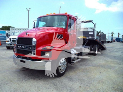 New red 2026 Mack MD6 rollback truck parked outdoors with chrome bumper and black grille, side mirrors, and a rollout bed behind the cab.