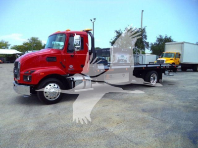 Red 2026 Mack MD6 rollback truck in a lot with other equipment visible in background.