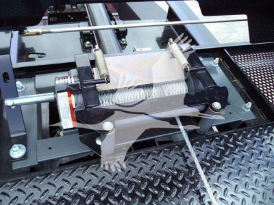 Truck rollback equipment with a spring-loaded winch mechanism and metal Diamond plate surface in view.