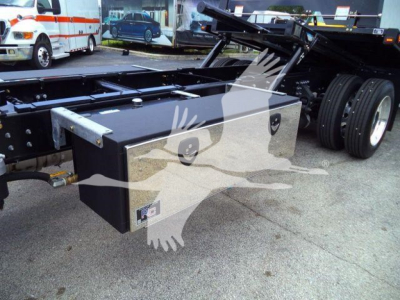 Chassis of a Mack MD6 rollback truck showing a large rectangular black toolbox mounted on the frame near the cab area.