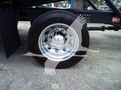 Wheel and tire assembly of a Mack MD6 truck showing polished steel wheel and black tire mounted on a rollback chassis.