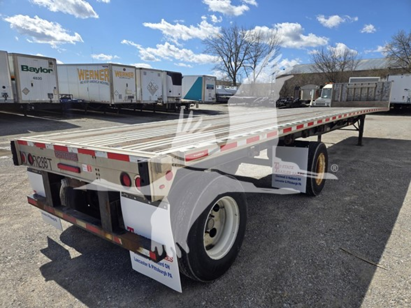 Flatbed trailer showing straight aluminum deck with dual rear axles and white wheels, side marker lights, and rear taillights; Fontaine Infinity trailer in yard.