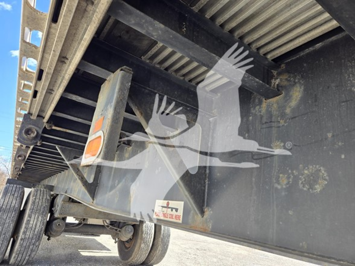 Flatbed trailer undercarriage showing deck rails, hitch, and rear wheel assembly with Fontaine label