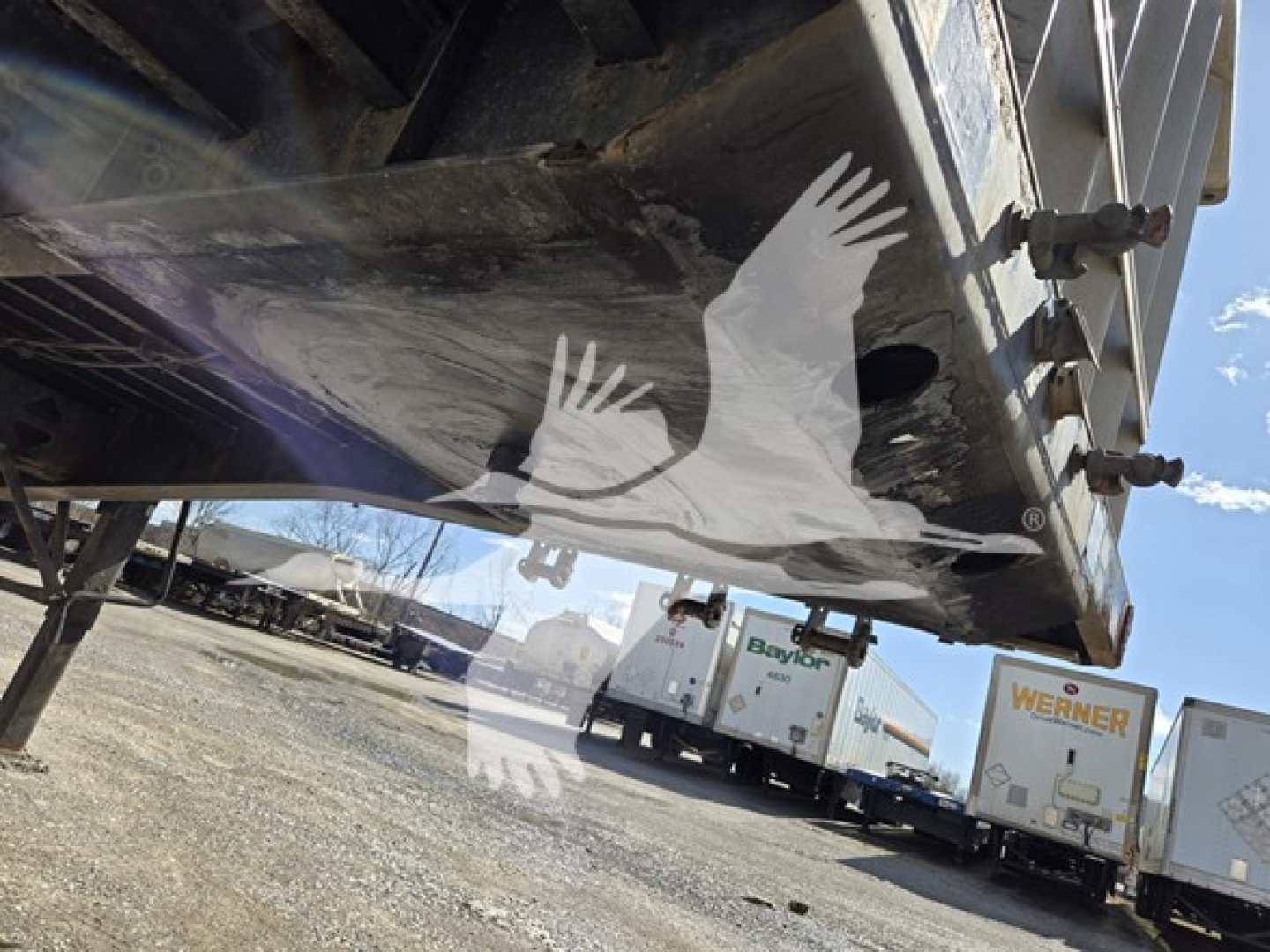 Trailer underside view showing Fontaine Infinity flatbed trailer in-service with visible bolts and frame structure.