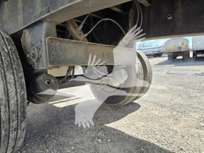 Trailer undercarriage with axle and suspension components; faint watermark of a logo over the image.