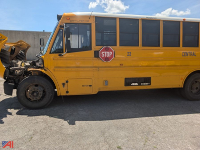 School bus side view showing yellow Freightliner chassis with stop sign, central lettering, doors, and wheel well.