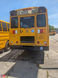 Rear view of a yellow Freightliner school bus showing emergency exit door, school bus signage, and handicap placard sticker.