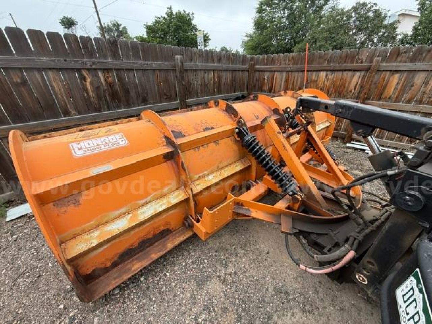 Snow plow blade attachment on a 1994 International 4900 truck with hydraulic linkage and orange paint.