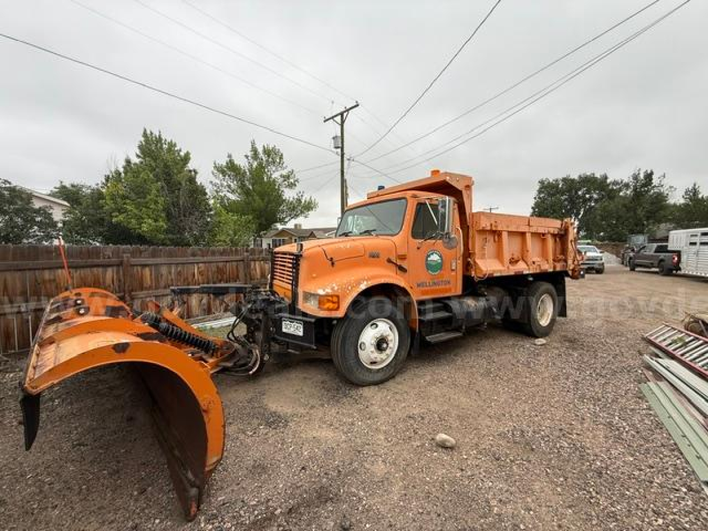 International 4900 truck with attached snow plow blade in front, orange dump bed, side view shows Vin: 1HTSDAAR4RH593721.