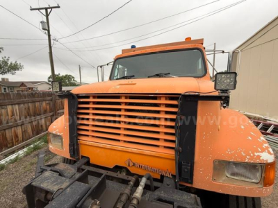 Front view of an orange 1994 International 4900 truck with plow equipment, large grille, side mirrors, and warning lights on the roof.