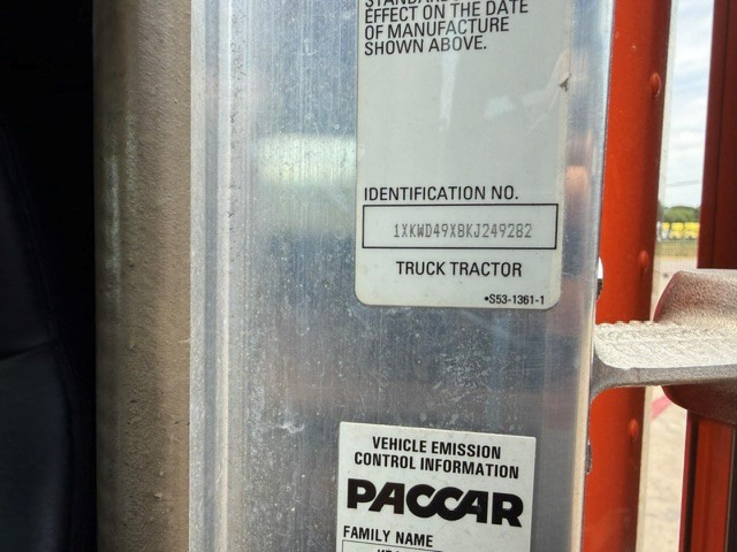 Truck door frame with vehicle identification stickers showing PACCAR Vehicle Emission Control Information and identification numbers.