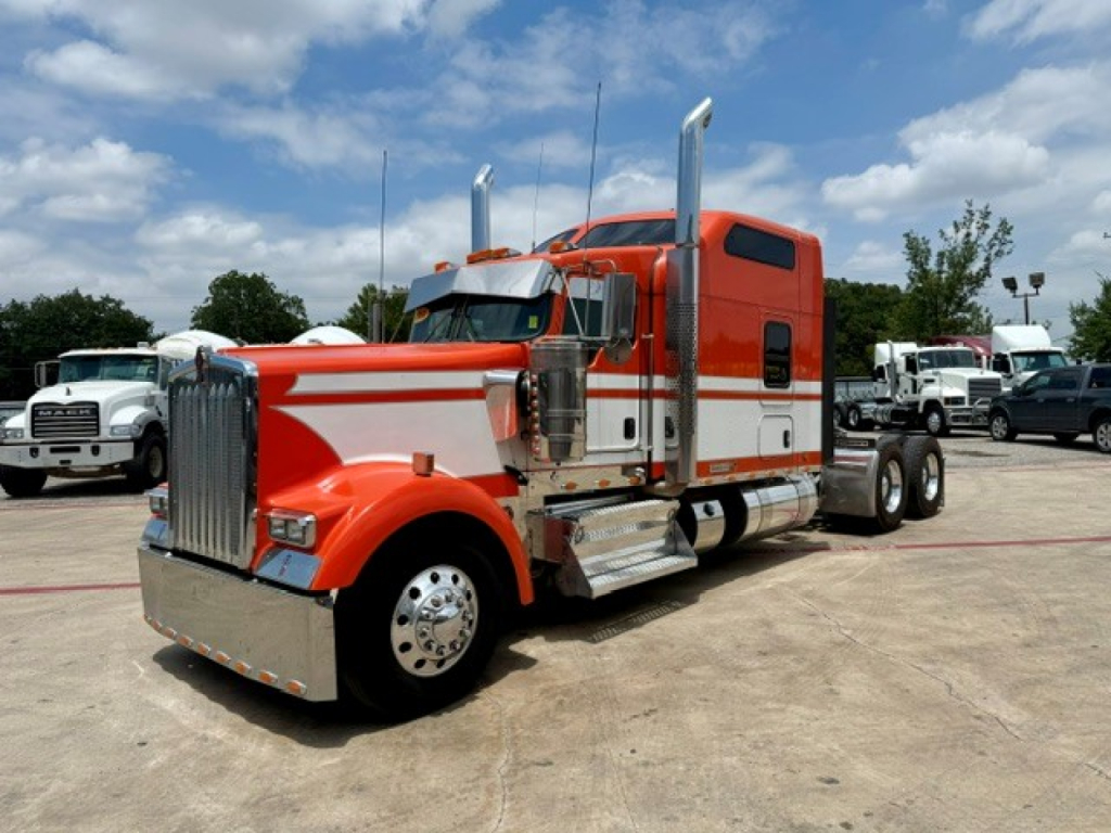 Kenworth W900 conventional sleeper truck in red with chrome accent and twin vertical exhaust stacks, front grill, and dual rear axles.