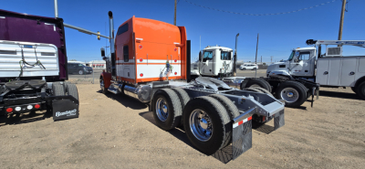 Kenworth W900 tractor rear view showing dual rear axles and fifth-wheel attachment in a truck lot
