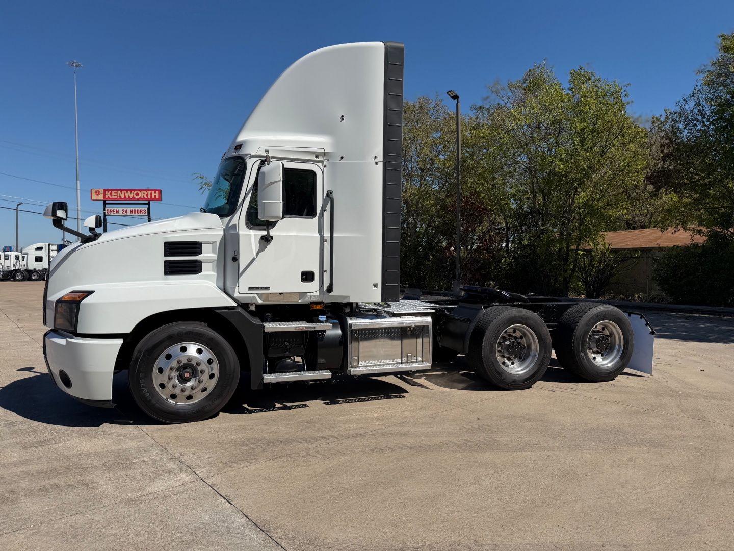 Mack Anthem 64T daycab tractor in side view showing cab, fuel tanks, and triple rear axles with wheels.