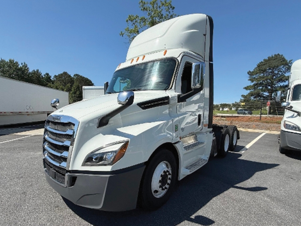 Truck cab showing Freightliner Cascadia 126 with sleeper, white exterior, grille and headlamps visible.