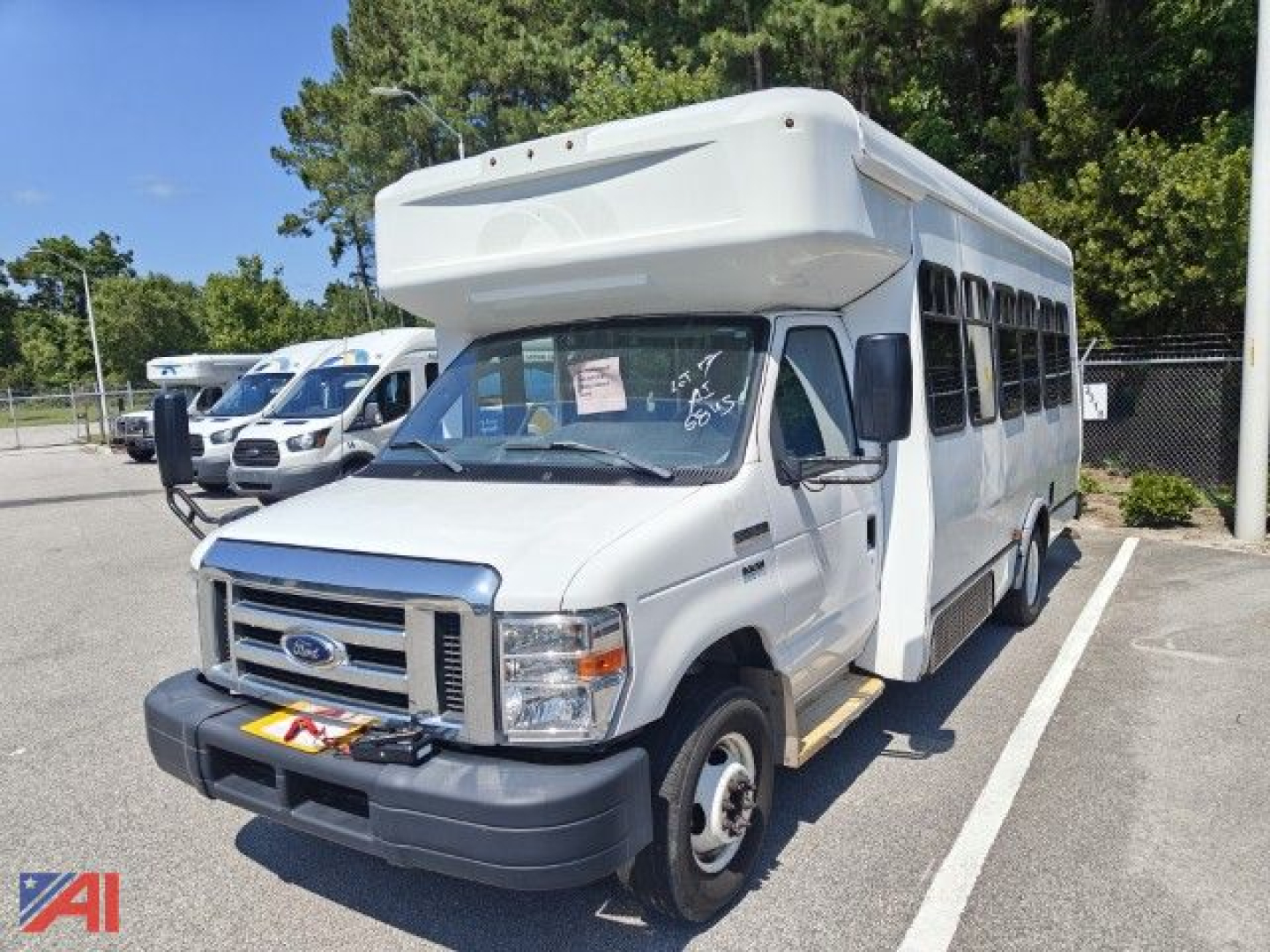 Ford E350 wheelchair bus in white, side view showing front cab and wheelchair access area, suburban lot.