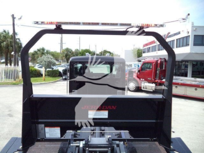 Truck bed area of a 2025 Kenworth T280 rollback unit with a black headache rack and chrome ladder rack; partial text on the rack shows 'JERRDAN' and a label on the toolbox.