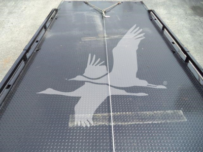 Truck bed with metal diamond plate surface and two birds logo graphic; tied rope at far end, seen from above; no engine components visible.