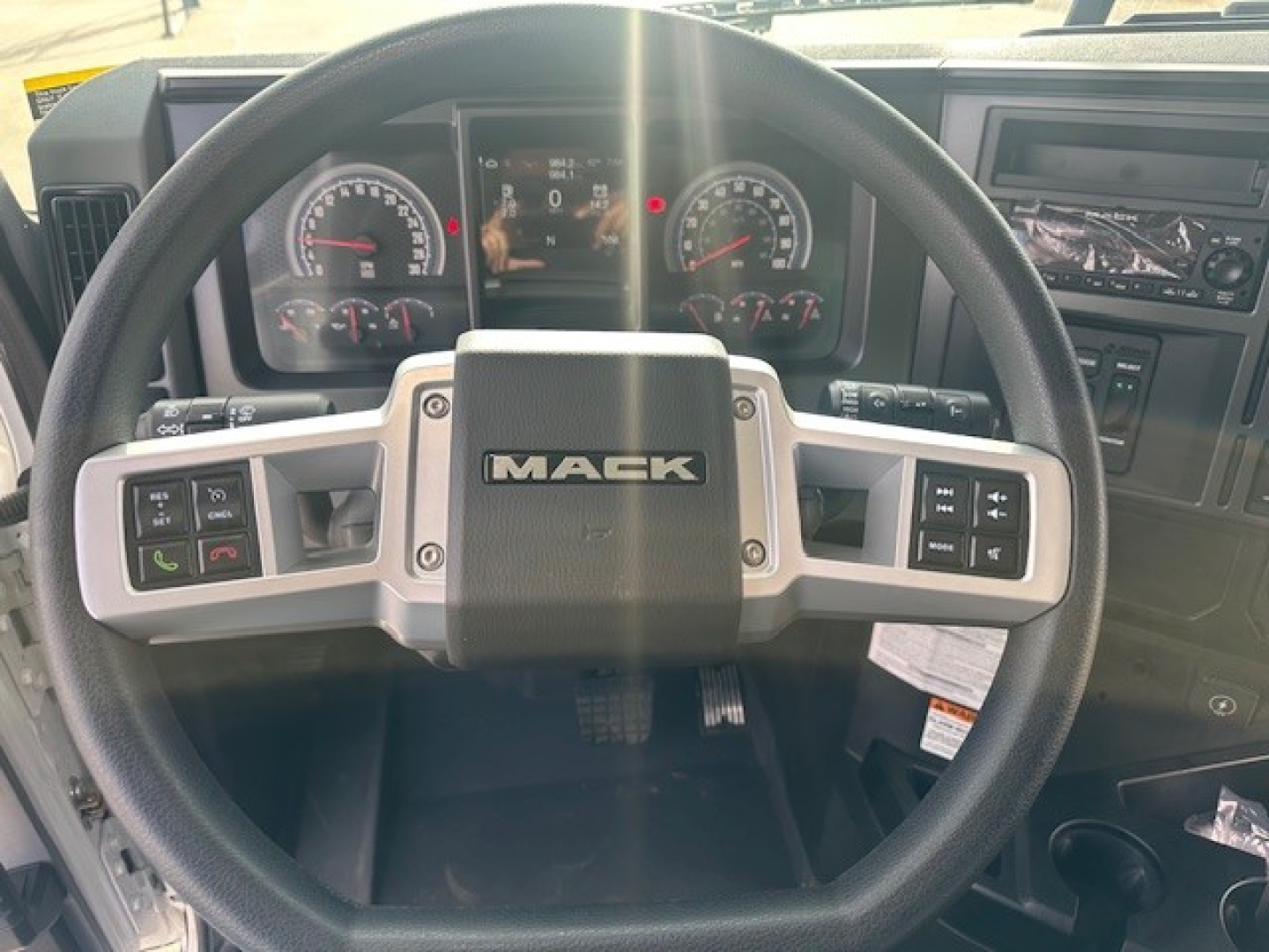 Mack GR64F steering wheel and instrument cluster showing dashboard controls and gauges.