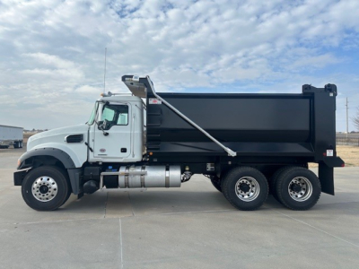 Mack GR64F dump truck side view showing black dump bed, white cab, dual rear axles and fuel tanks.