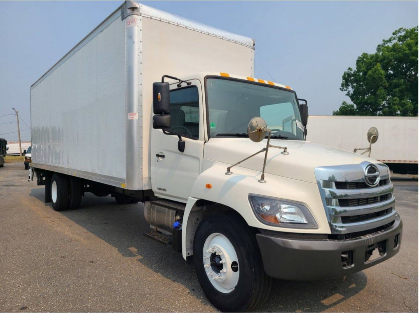 Hino box truck side/front view showing cab, large box body, and cargo area with dual rear wheels.
