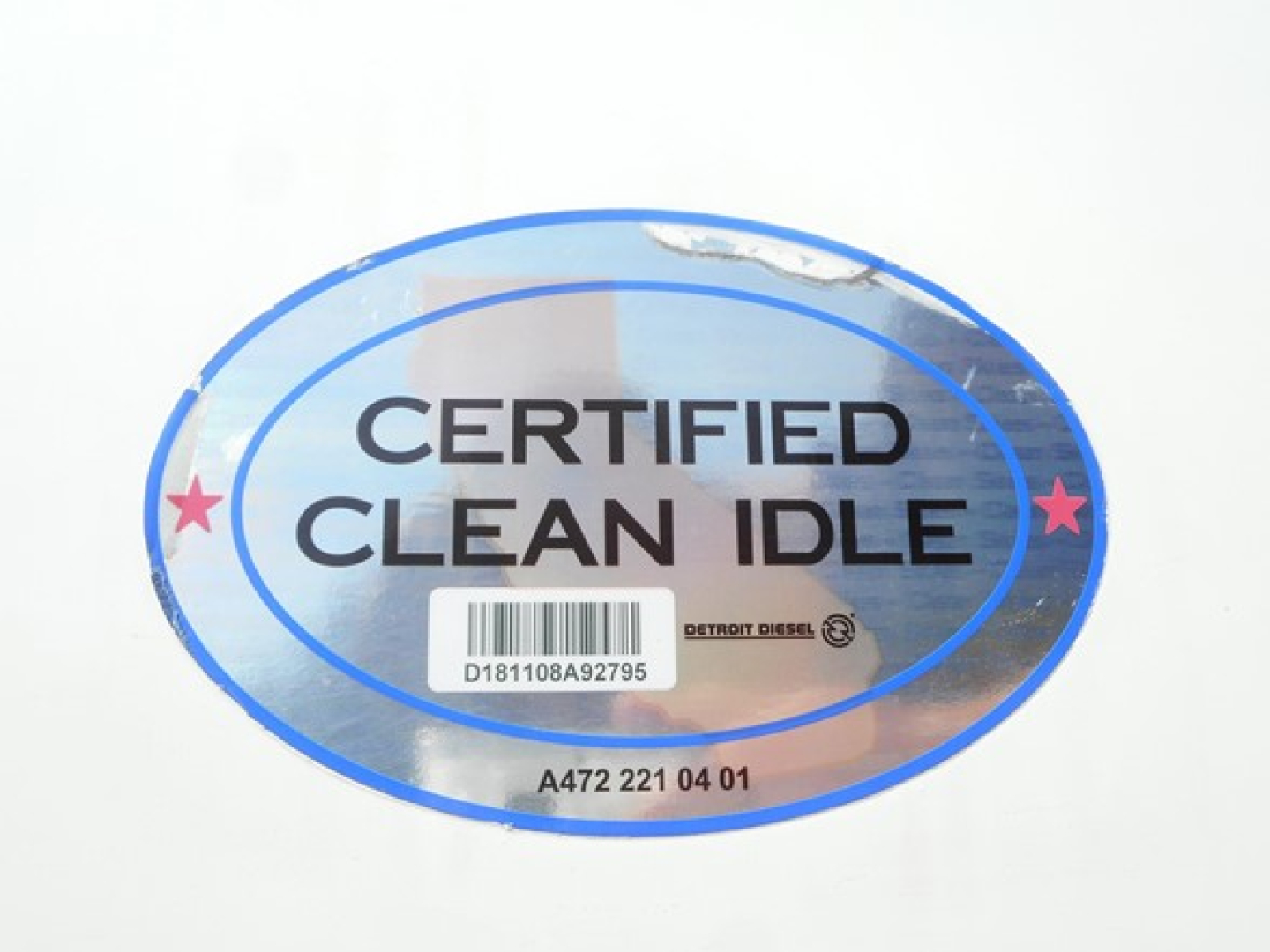 Oval sticker reading CERTIFIED CLEAN IDLE with barcode and small 'Detroit Diesel' text, blue gradient with pink stars, lot number A472 221 04 01.