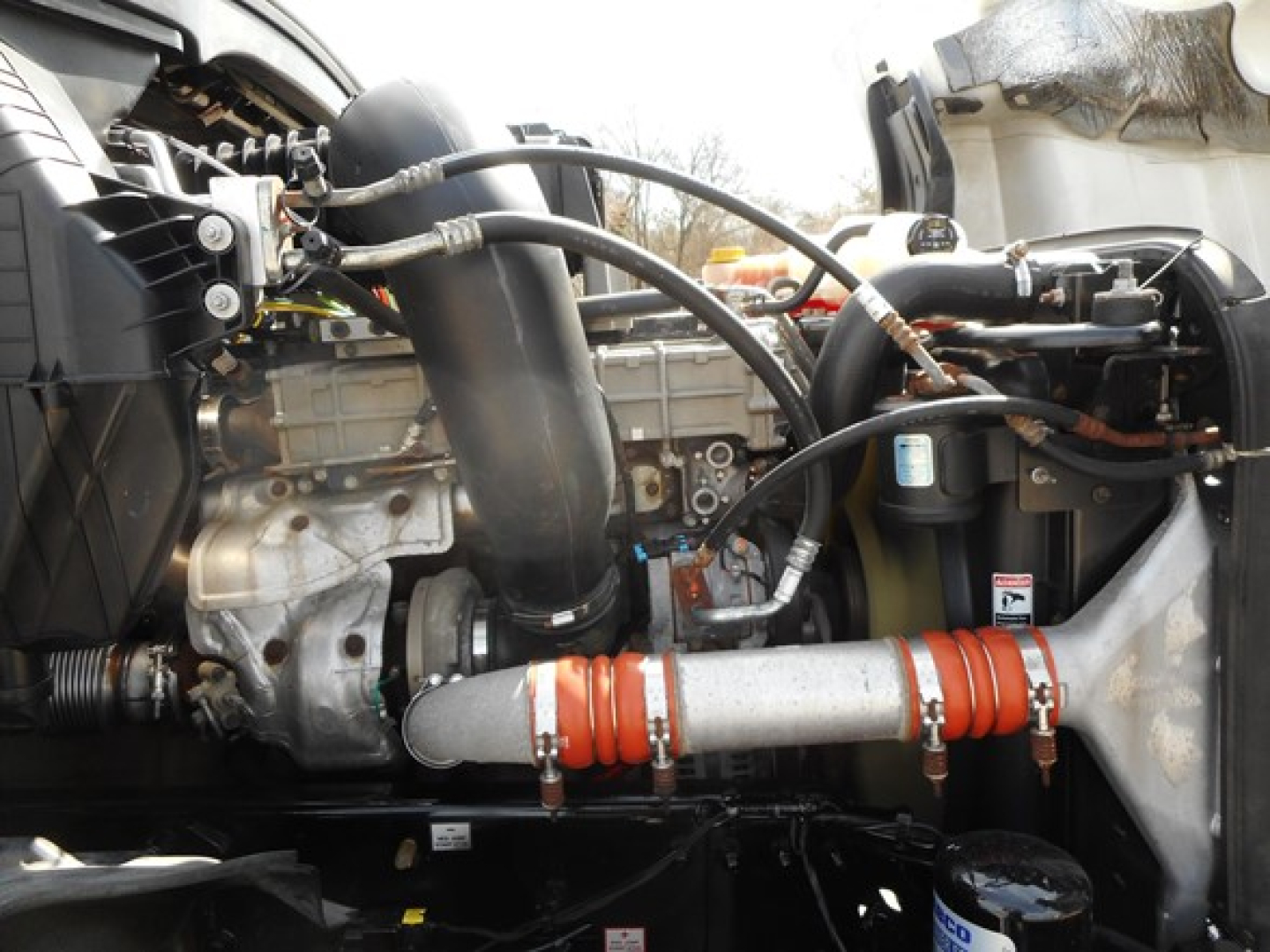 Truck engine bay showing intake manifold and various hoses in Freightliner Cascadia 126 engine compartment.