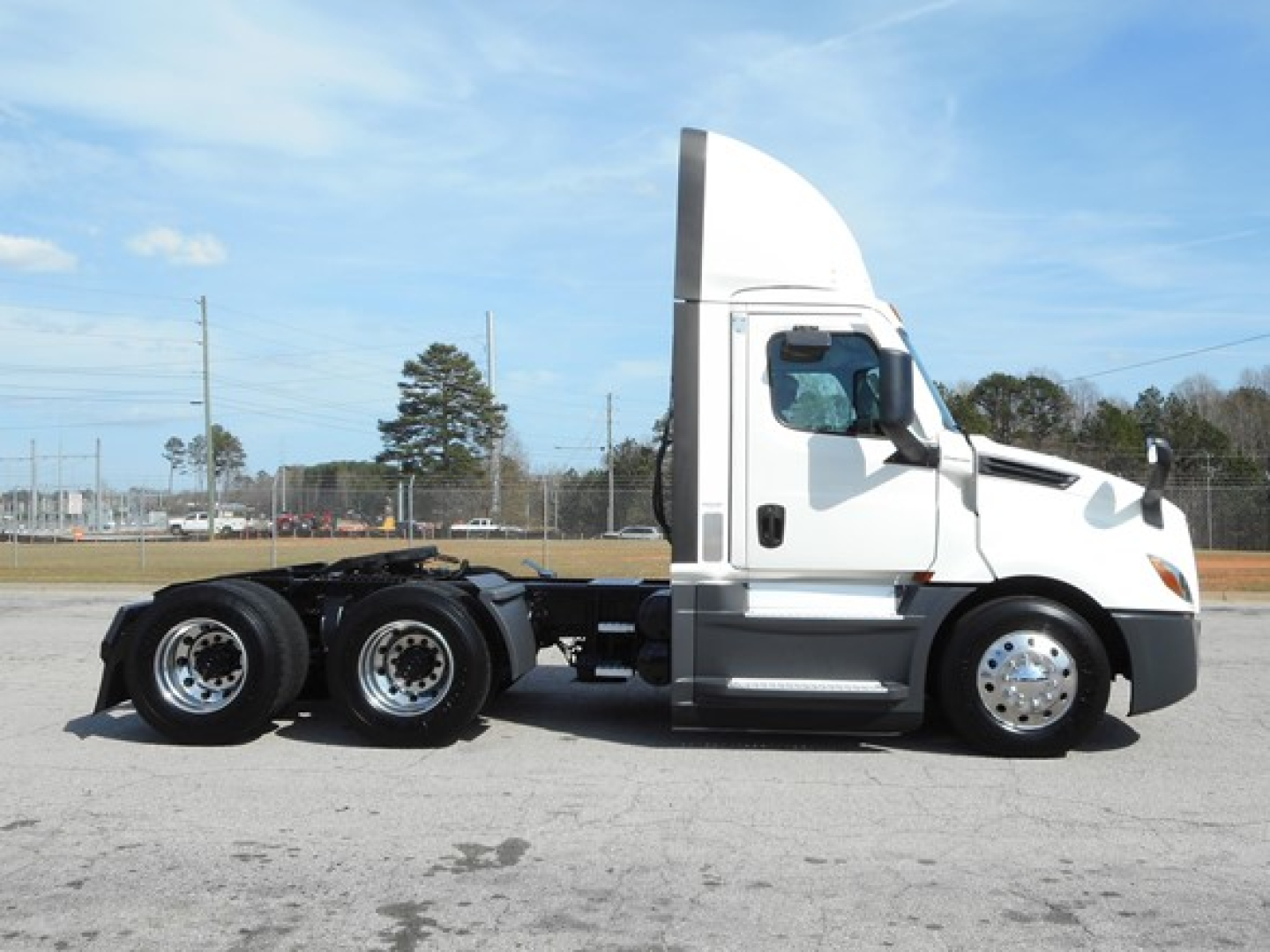 Truck side view showing 2021 Freightliner Cascadia 126 tractor with white cab and dual rear axles